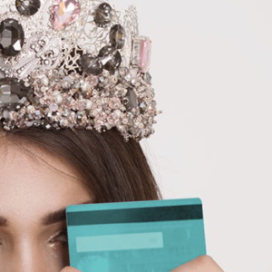 Woman with a bejeweled crown and a credit card over her face