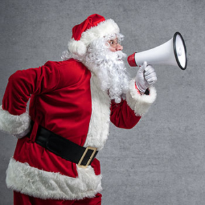 Santa Claus in full outfit using a white megaphone 