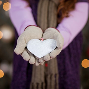 gloved hands holding a white heart-shaped ornament