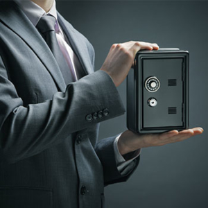 Bottom half of man in a grey suit holding a small safe in both hands