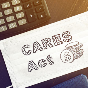 "Cares act" and a drawing of coins written on a general white mask on top of a table