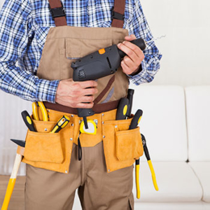 man with work apron and toolbelt holding an automatic screwdriver