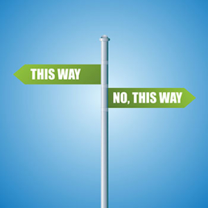 metal pole with green street sign pointing to the left saying 'this way' and one green street sign pointing to the right saying 'no, this way' 