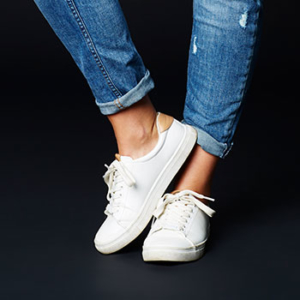 person's white sneakers and jean wearing calves against a black background