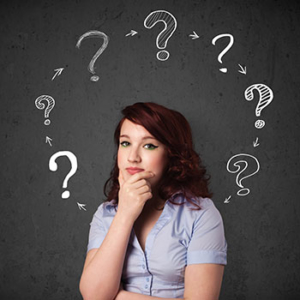 chalkboard background with cycle of white chalked question marks behind a young women looking perplexed