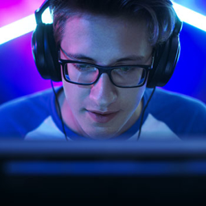 man staring down at computer screen with glasses and video gaming headphones