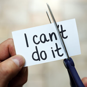 A person is using scissors to cut through a white piece of paper changing the saying from, "I can't do it" to "I can do it"